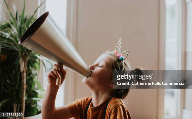 a young girl has fun with an old fashioned metal megaphone - alardear fotografías e imágenes de stock