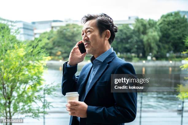 公園でスーツを着たビジネスマンがスマートフォンで電話をかける - businessman in suit ストックフォトと画像