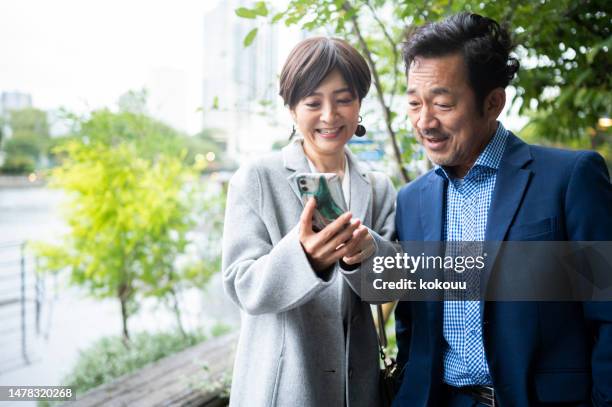 スマートフォンをチェックする笑顔の中年夫婦 - 夫婦 ストックフォトと画像