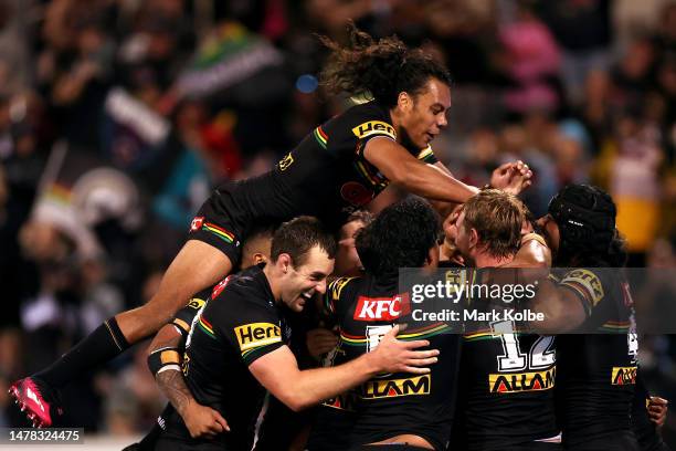 Jarome Luai of the Panthers jumps on his team mates as they celebrate with Jaeman Salmon of the Panthers after he scored a try during the round five...