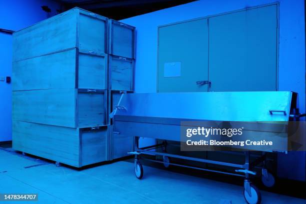 a stack of coffins and a mortuary trolley - enterrado fotografías e imágenes de stock
