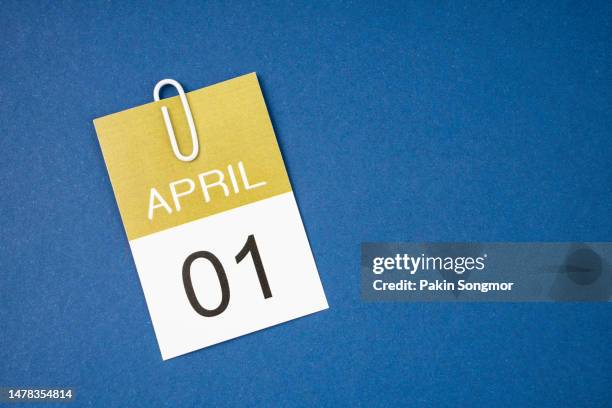 calendar page for april 1st with a paper clip against a dark blue background. - april fool photos et images de collection