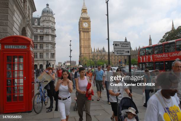 Cycliste et touristes sur Parliament Square. Au fond, Big Ben et le parlement. Icone de Londres, les cabines telephoniques rouges tendent a...