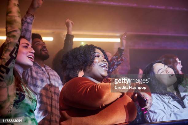 group of people enjoying an evening out at a music venue. - crowd excitement stock pictures, royalty-free photos & images
