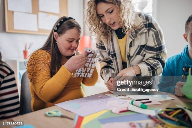 les personnes atteintes du syndrome de down et de paralysie cérébrale font un projet artistique avec l’aide d’assistants et d’animateurs. atelier d’art sur les soins de santé aux personnes handicapées. - animateur de dessins animés photos et images de collection