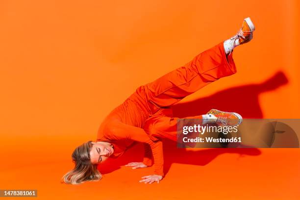 woman breakdancing against orange background - breaking stock pictures, royalty-free photos & images
