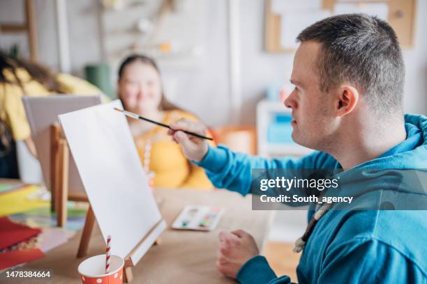 disability health care art workshop.creative painting on canvas and down syndrome people and cerebral palsy doing an art project - developmental disability stock pictures, royalty-free photos & images