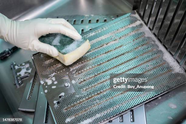 someone using a scrub sponge to cleaning a dirty cooker hood filters at the sink. - dirty oven stock pictures, royalty-free photos & images