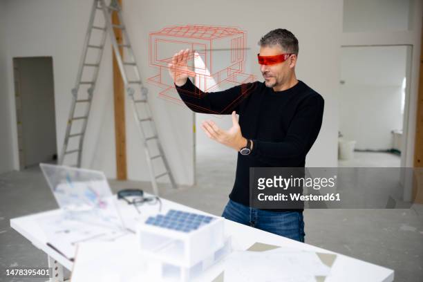 architect wearing virtual reality simulator examining house model and gesturing at construction site - austria stock illustrations