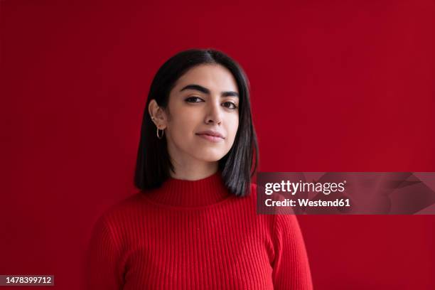 confident young woman against red background - monocromo vestimenta fotografías e imágenes de stock