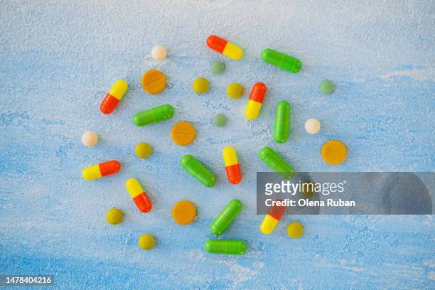 colored pills and capsules on painted surface. - scatter stock-fotos und bilder