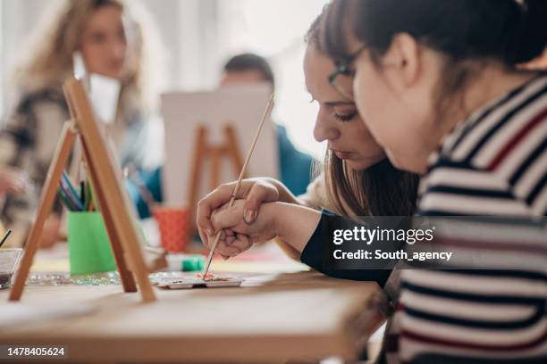 kunstworkshop für menschen mit behinderungen im gesundheitswesen. kreatives malen auf leinwand und down-syndrom-menschen und zerebralparese bei einem kunstprojekt - behindertenwerkstatt stock-fotos und bilder