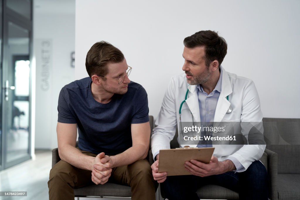 Mature doctor discussing with man at clinic