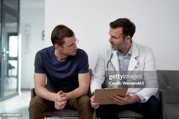 mature doctor discussing with man at clinic - man talking to doctor bildbanksfoton och bilder