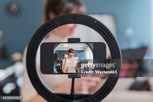 Vlogger recording make-up tutorial through smart phone mounted on ring light at home Vlogger recording make-up tutorial through smart phone mounted on ring light at home