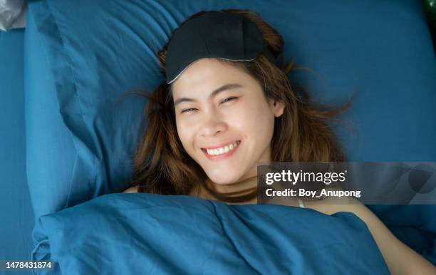 happiness asian woman smiling while lying on her bed. - pillow over head 個照片及圖片檔