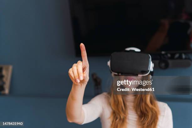 woman wearing virtual reality headset gesturing at home - 人差し指 女性 ストックフォトと画像