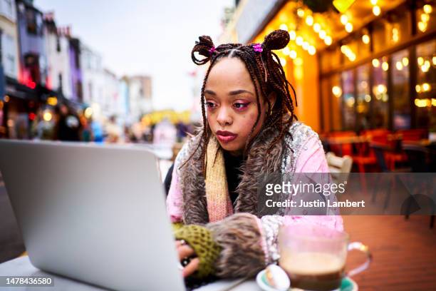 young woman working on a laptop outside a cafe - lambert stock pictures, royalty-free photos & images