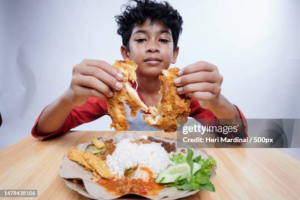 boy eats fried chicken with rice and vegetables,bali,ireland - heri mardinal stock pictures, royalty-free photos & images