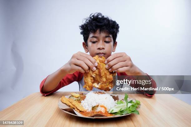 boy eats fried chicken with rice and vegetables,bali,ireland - heri mardinal stock pictures, royalty-free photos & images