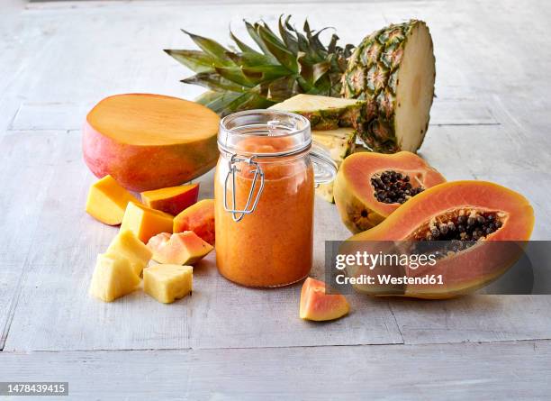 halved mango fruit, papaya, pineapple and smoothie in jar - papaya stock-fotos und bilder