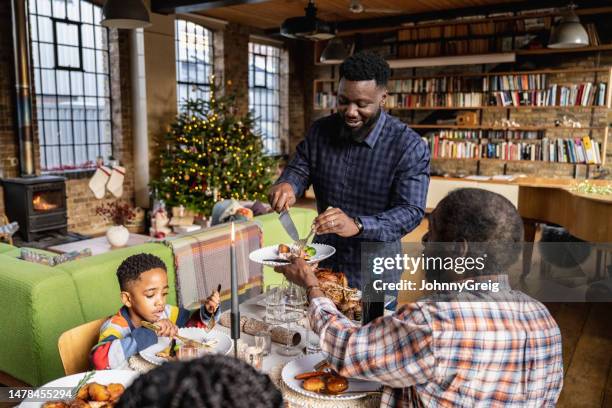 father serving roast turkey dinner to three generations at christmas lunch - 1141 65 stockfoto's en -beelden