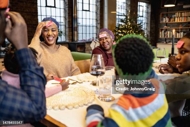 family play guessing game at christmas with names of animals on their foreheads - holiday table stock pictures, royalty-free photos & images