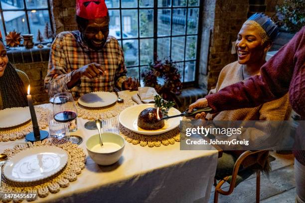 christmas pudding doused in brandy being lit at dining table - christmas pudding stockfoto's en -beelden