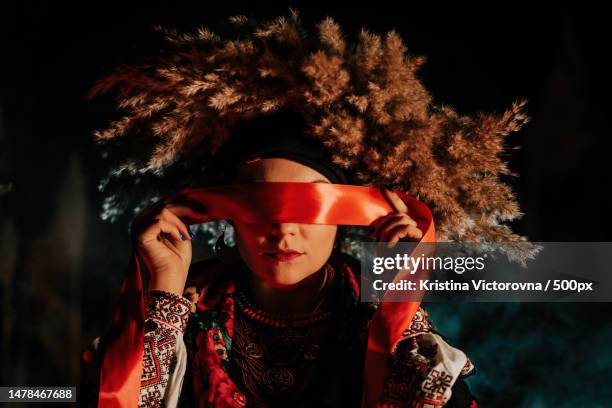 ukrainian woman ties red ribbon around eyes as on ritual doll motanka - dolly reed stock pictures, royalty-free photos & images