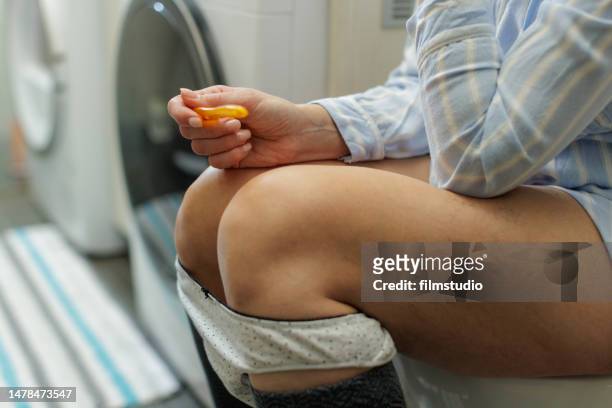 unkenntliche frau, die auf der toilette sitzt und auf schwangerschaftstestergebnisse wartet - ovulation stock-fotos und bilder
