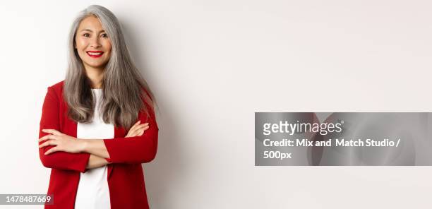 business people smiling asian senior woman in red blazer,cross arms - red blazer stock pictures, royalty-free photos & images
