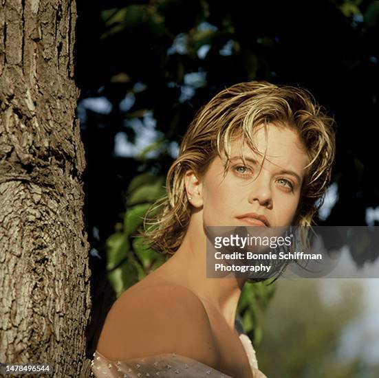 Actor Meg Ryan looks into the sunlight as she leans against a tree in Los Angeles in 1987.