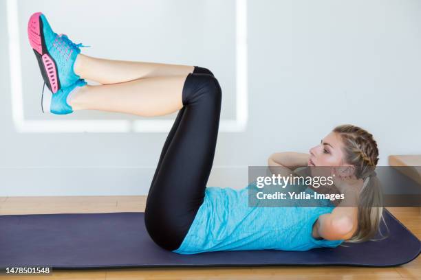 blond woman in blue doing crunches on yoga mat - stereotipo foto e immagini stock