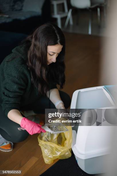 femme nettoyant la litière pour chat avec une pelle - récipient de déchets médicaux photos et images de collection