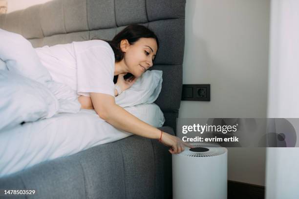 woman is turning on air purifier in bedromm - ventilator illustration stock pictures, royalty-free photos & images