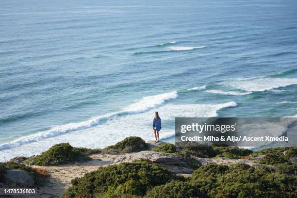 young woman stands on hill above surf - azenhas do mar stock-fotos und bilder