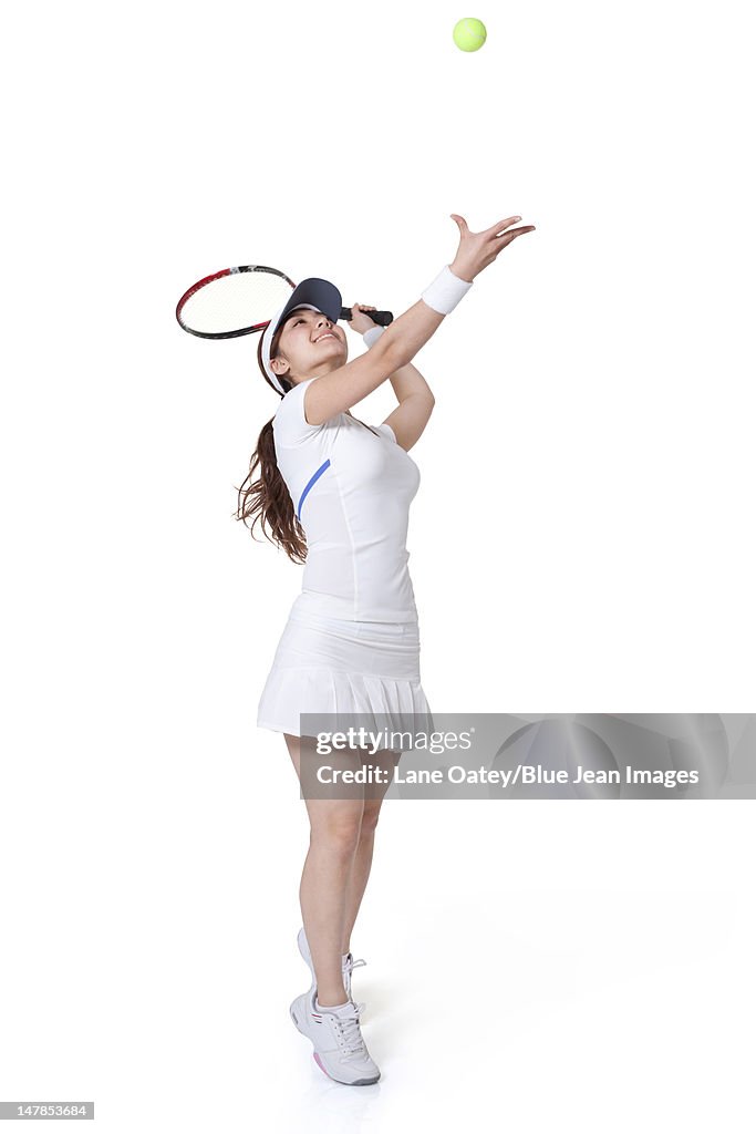 Young woman serving a tennis ball