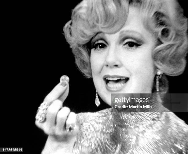 American comedienne, actress, singer and businesswoman, Edie Adams , holds a coin as she invades Wall Street in search of "Big Spenders" in the new...
