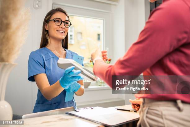 woman paying for beauty treatment at a salon - paying doctor stock pictures, royalty-free photos & images