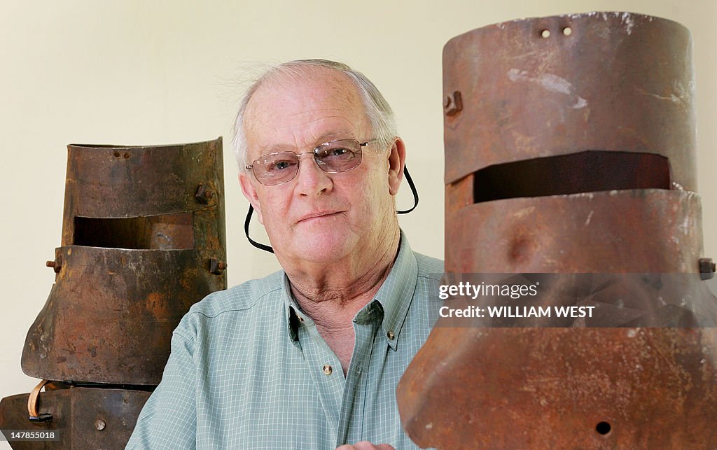 Mike Hastings poses between the helmets