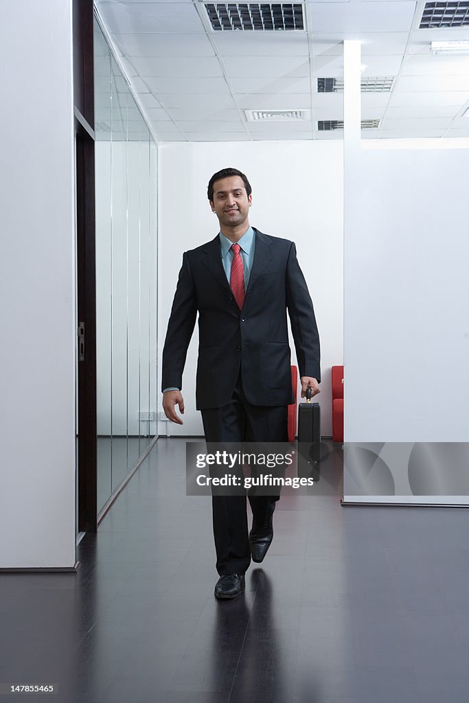 Businessman with briefcase walking at the office hallway