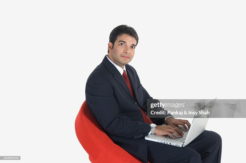 Young businessman using laptop, side view