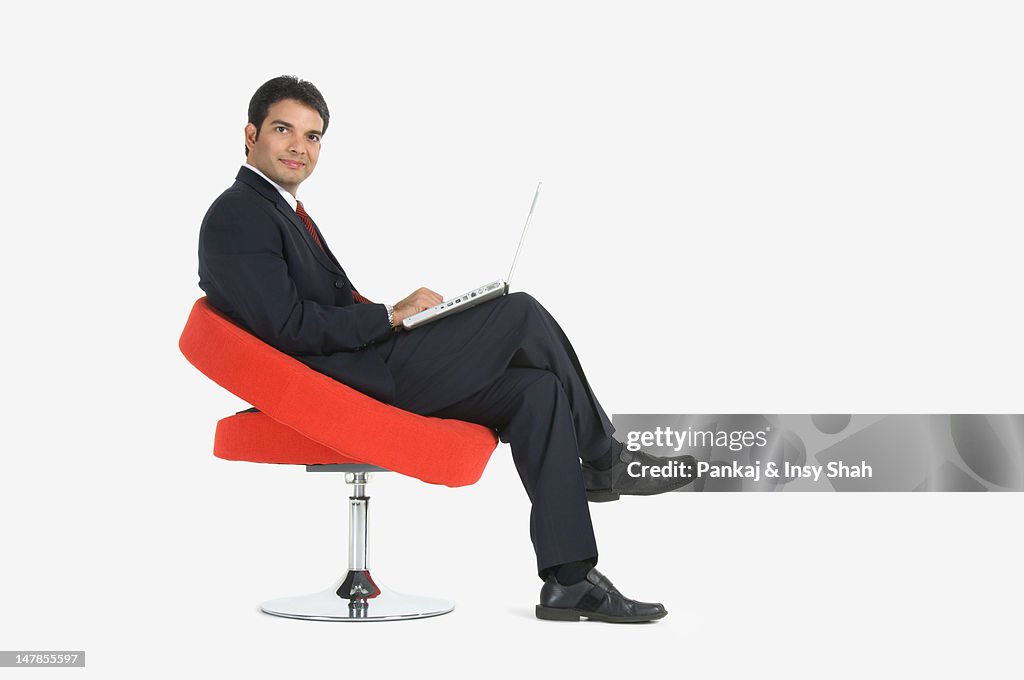 Young businessman using laptop, side view