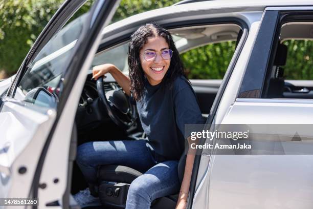 joven latina tratando de salir de un coche. ella se ríe - perspectiva de un coche fotografías e imágenes de stock