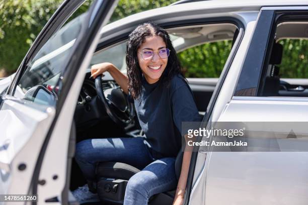 jovem mulher latina tentando sair de um carro. ela está rindo - alegria - fotografias e filmes do acervo