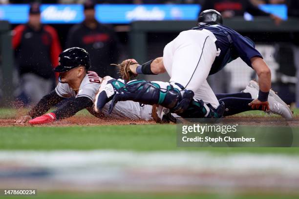 Andres Gimenez of the Cleveland Guardians scores past Cal Raleigh of the Seattle Mariners during the second inning at T-Mobile Park on March 31, 2023...