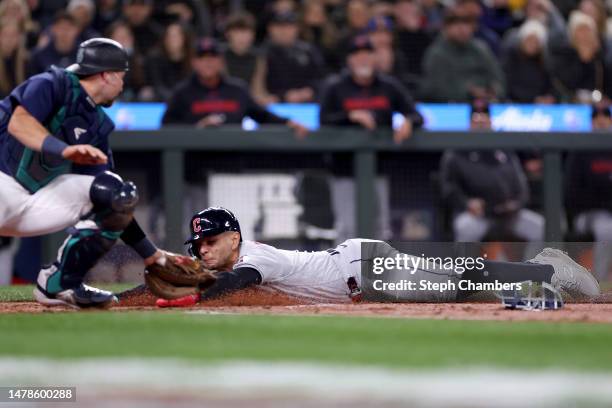 Andres Gimenez of the Cleveland Guardians scores past Cal Raleigh of the Seattle Mariners during the second inning at T-Mobile Park on March 31, 2023...