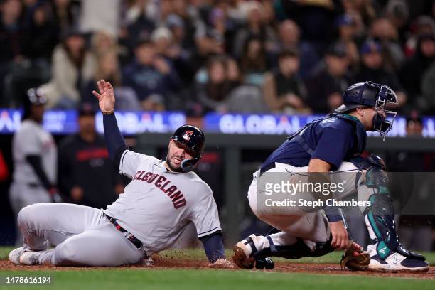 Mike Zunino of the Cleveland Guardians scores against Cal Raleigh of the Seattle Mariners during the fifth inning at T-Mobile Park on March 31, 2023...