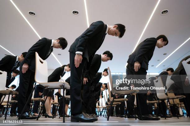 Newly hired employees for All Nippon Airways group companies bow during an entrance ceremony at the ANA Blue Base facility on April 01, 2023 in...