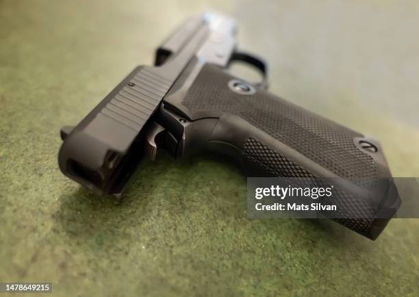 handgun lying on table - armi da fuoco foto e immagini stock